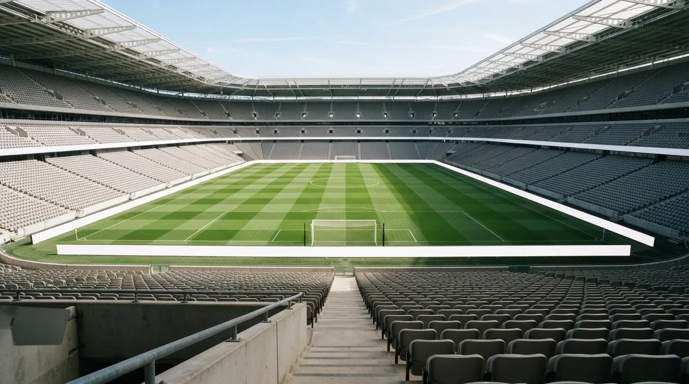 Ein leeres Fußballstadion bei Tageslicht von der Tribüne aus gesehen, der Rasen zeigt gleichmäßige Mähstreifen.