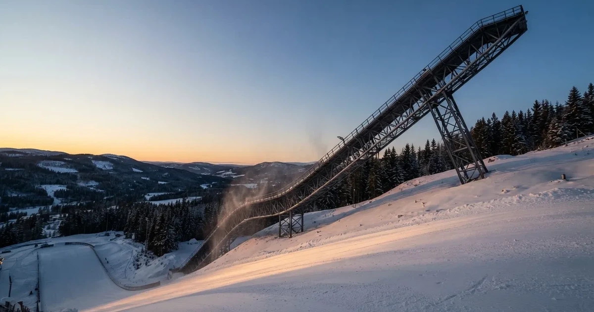 Eine Skisprungschanze im Schnee, von unten gesehen, vor einem klaren Winterhimmel in der Dämmerung, ohne Menschen.