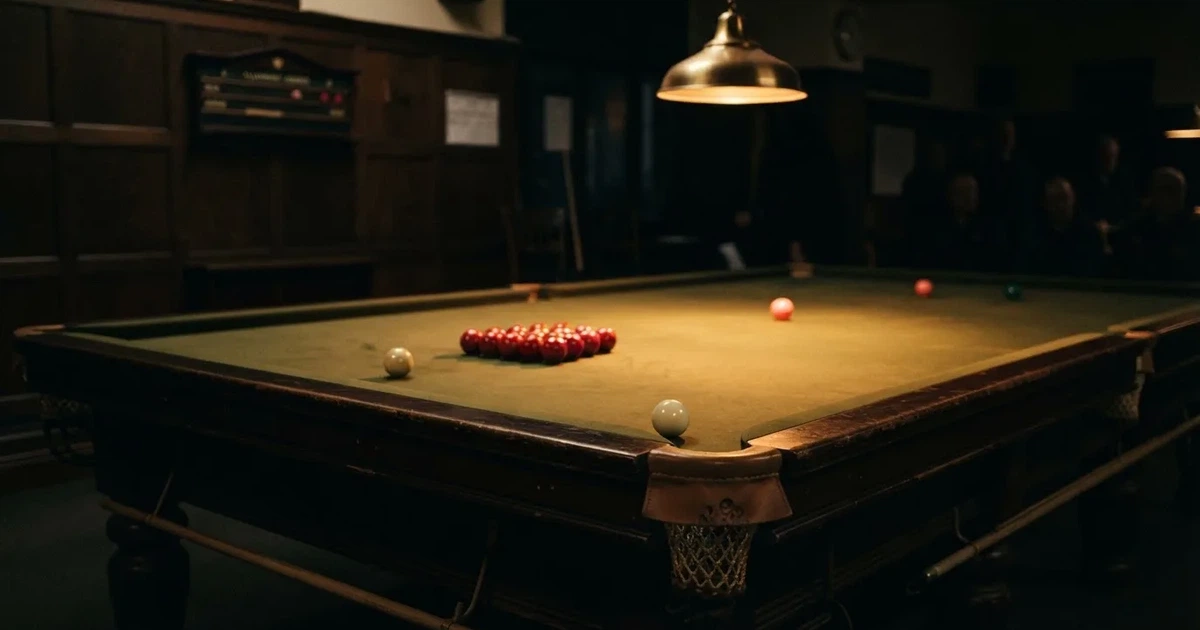 Ein Snookertisch mit grünem Tuch und aufgebauten roten Kugeln in einem abgedunkelten Raum unter einer hängenden Lampe.