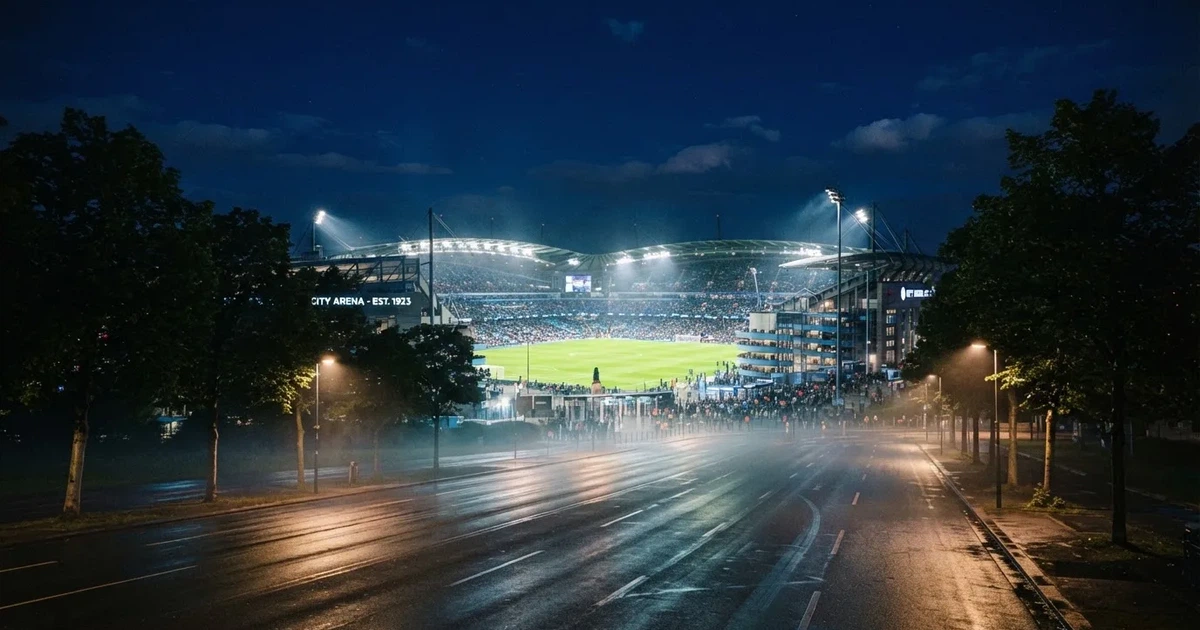 Ein Fußballstadion bei Nacht aus großer Entfernung, hell erleuchtet unter Flutlicht, davor eine dunkle Straße und Bäume.